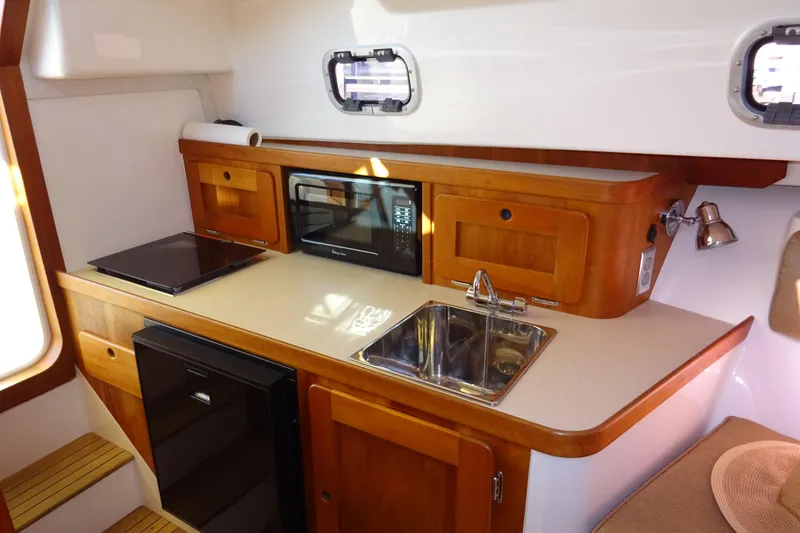 Slide: The Image of 2007 Hunt Yachts Surfhunter 29 interior kitchen with sink, microwave, and wooden cabinetry. - 46