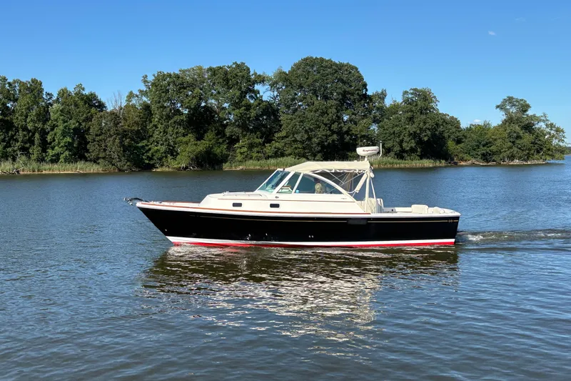 Slide: The Image of 2007 Hunt Yachts Surfhunter 29 cruising on a serene lake with lush green trees. - 5