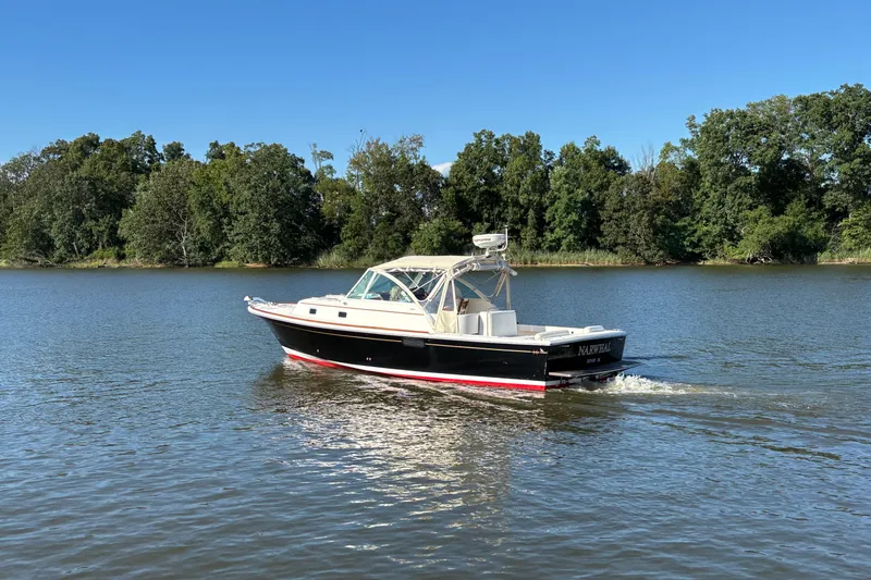 Slide: The Image of 2007 Hunt Yachts Surfhunter 29 cruising on a serene lake with lush green trees. - 6