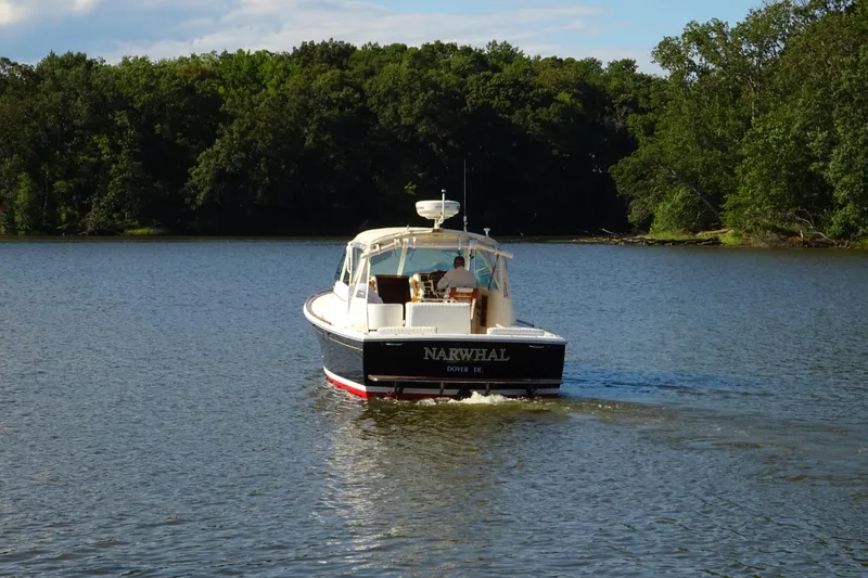 Slide: The Image of 2007 Hunt Yachts Surfhunter 29 cruising on a serene lake with lush forest backdrop. - 7