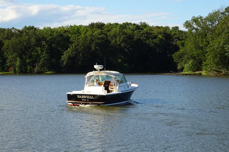 Slide: The Image of 2007 Hunt Yachts Surfhunter 29 cruising on a serene lake with lush green trees. - 8