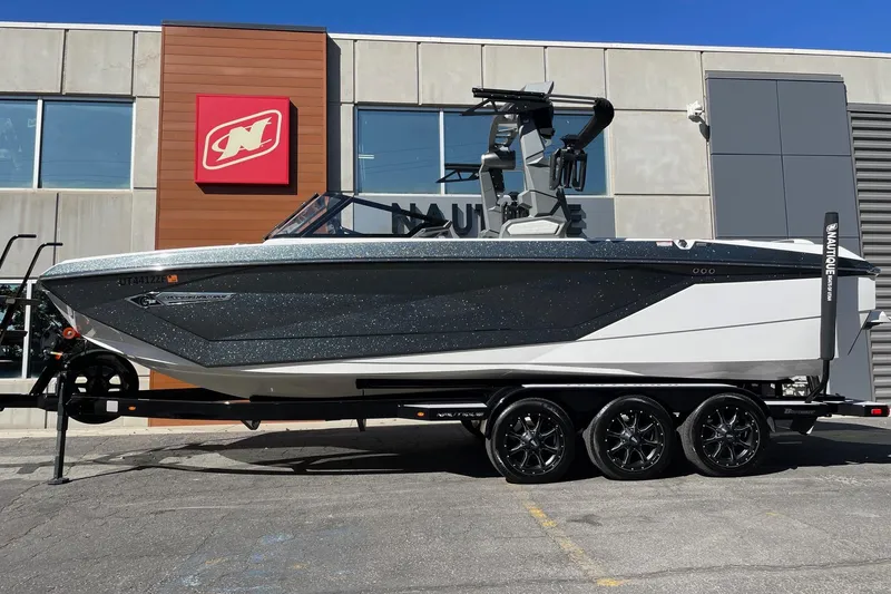 The Image of 2023 Nautique Super Air Nautique G25 boat on trailer, parked outside dealership. - 1