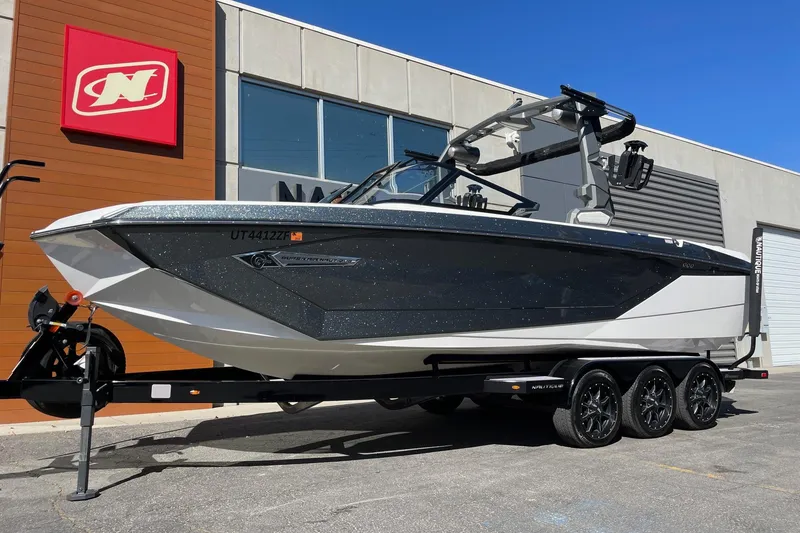 Slide: The Image of 2023 Nautique Super Air Nautique G25 boat on trailer outside dealership. - 2