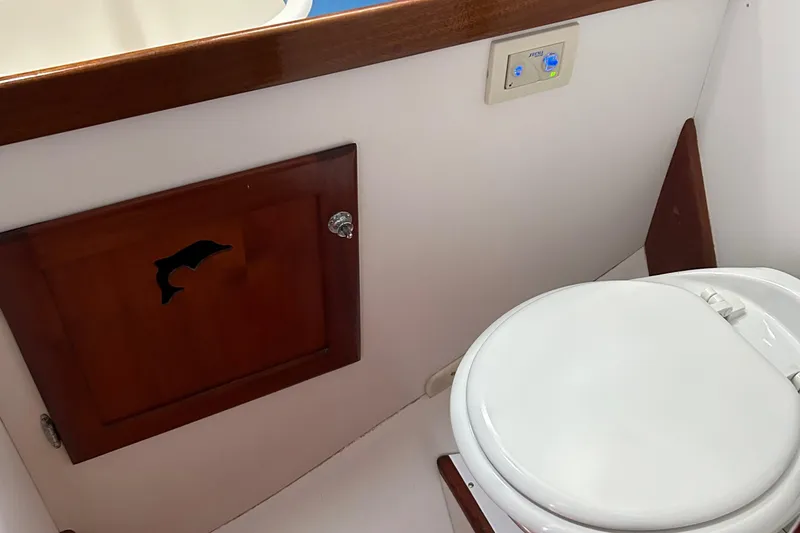 Slide: The Image of 1987 Lyman-Morse Downeast Flybridge boat bathroom with wooden cabinet and white toilet. - 21