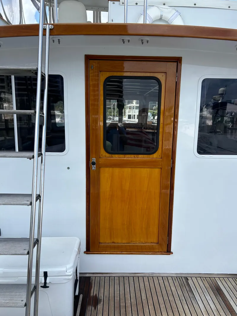 Slide: The Image of 1987 Lyman-Morse Downeast Flybridge yacht with wooden door and white exterior. - 25
