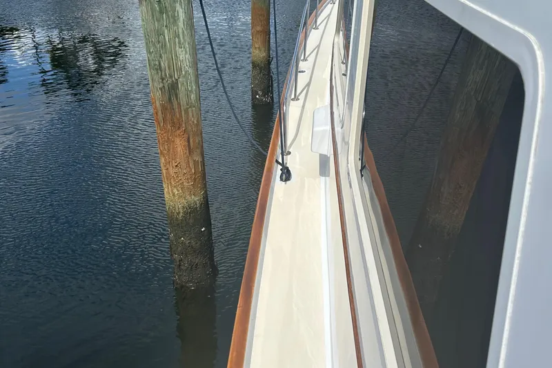 Slide: The Image of 1987 Lyman-Morse Downeast Flybridge yacht docked, showing side deck and water reflections. - 37
