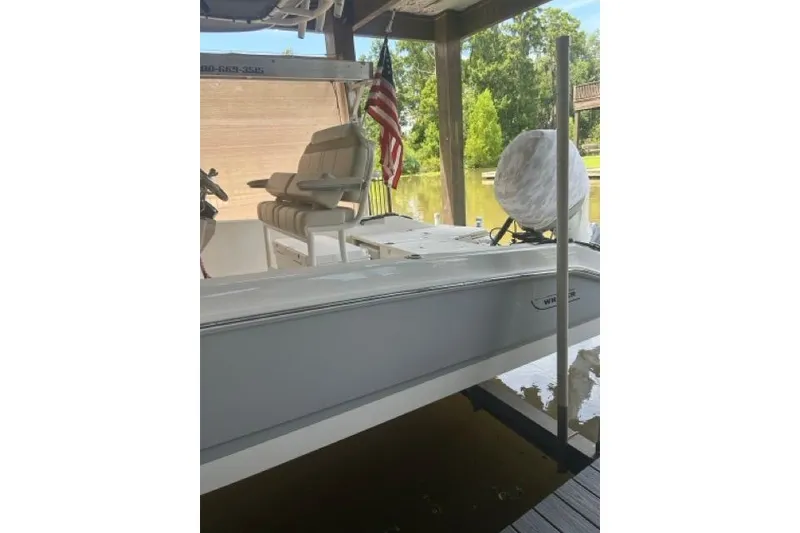 Slide: The Image of 2024 Boston Whaler 250 Dauntless boat docked under a covered area with American flag. - 7