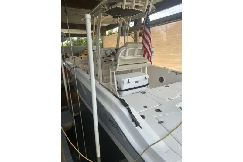 Slide: The Image of 2024 Boston Whaler 250 Dauntless boat with American flag, docked under shelter. - 9