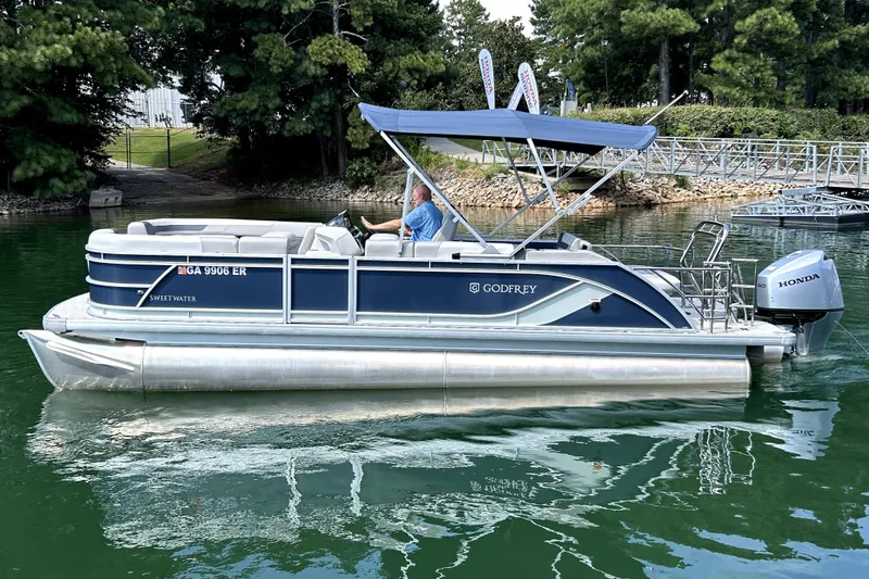 Slide: The Image of 2025 Godfrey SWEETWATER 2286 SFL pontoon boat on a serene lake. - 3