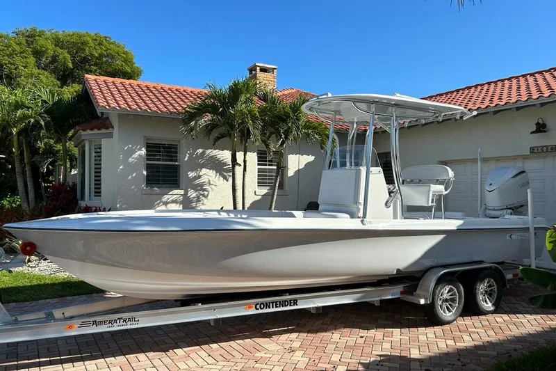 The Image of 2024 Contender 26 Bay boat on trailer, parked in front of a house with palm trees. - 0