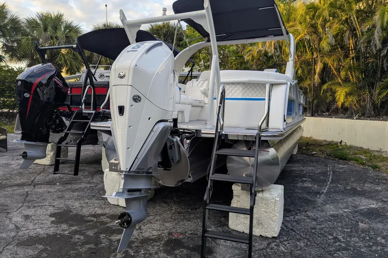 Slide: The Image of 2026 Trifecta 25 RF SS Arch pontoon boat with dual outboard motors, parked outdoors. - 21