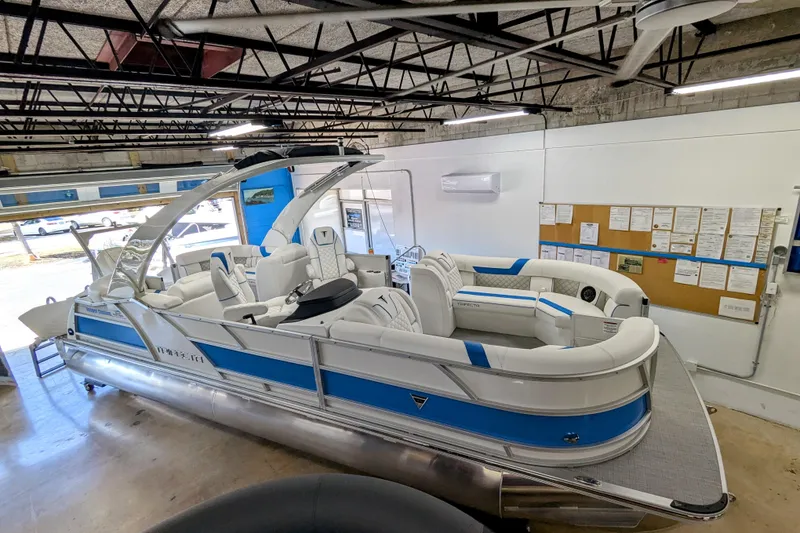 Slide: The Image of 2026 Trifecta 25 RF SS Arch pontoon boat in showroom, featuring sleek white and blue design. - 3