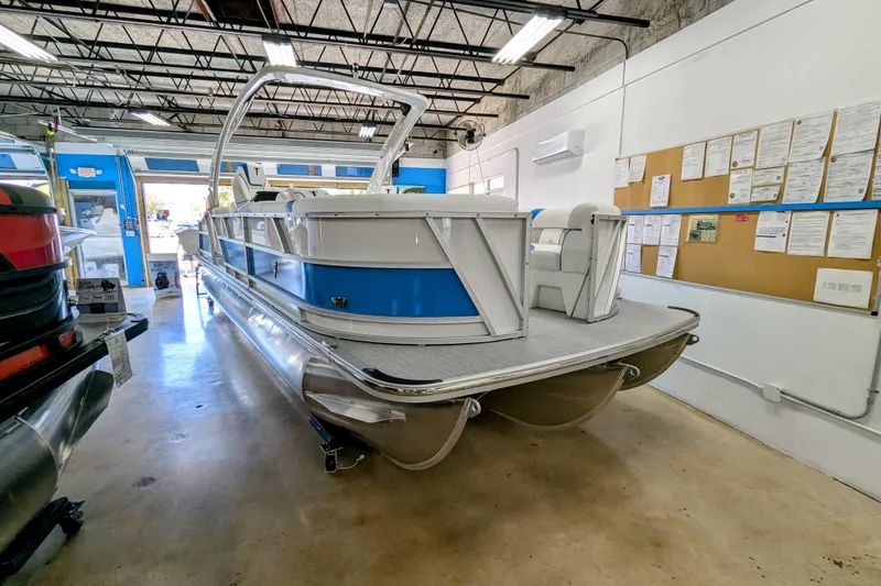 Slide: The Image of 2026 Trifecta 25 RF SS Arch pontoon boat in showroom, blue and white design. - 4