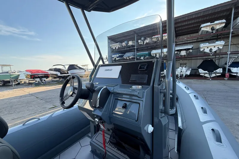 Slide: The Image of 2025 Highfield Sport 660 boat interior with steering wheel and control panel, docked near other boats. - 10