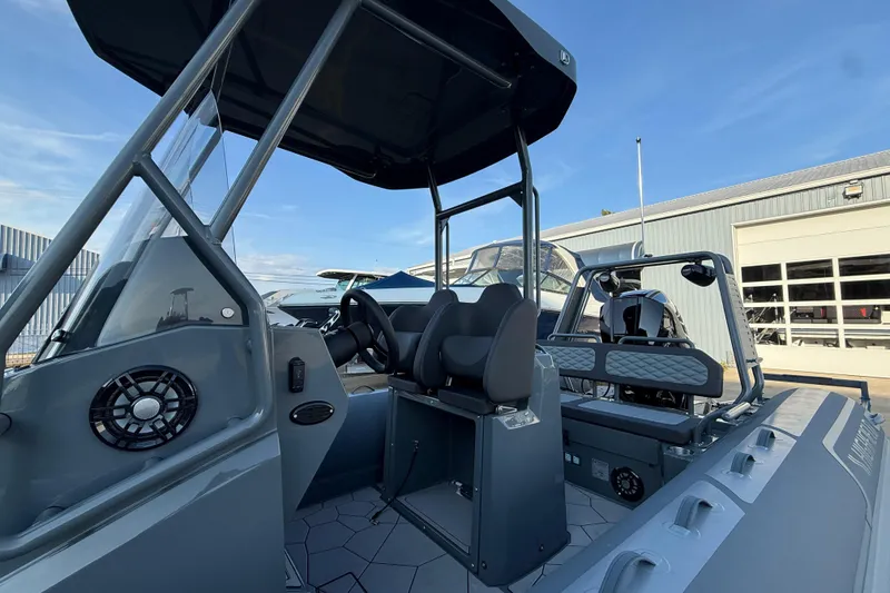 Slide: The Image of 2025 Highfield Sport 660 boat interior with seating and steering console, docked outdoors. - 12