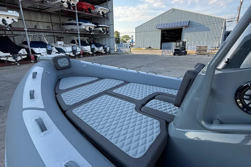 Slide: The Image of 2025 Highfield Sport 660 boat interior with quilted seating, docked near a storage facility. - 13