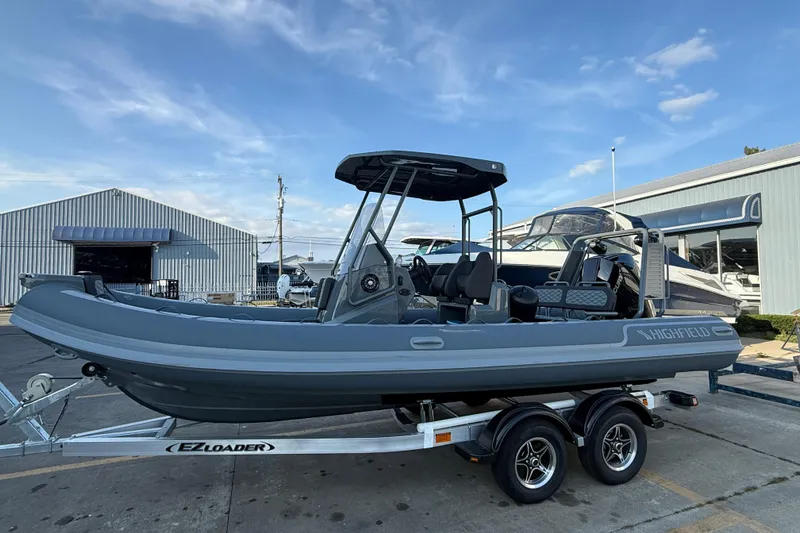 Slide: The Image of 2025 Highfield Sport 660 boat on trailer, parked near industrial buildings under blue sky. - 7