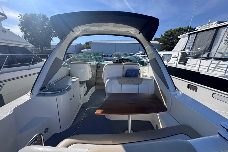 Slide: The Image of 2008 Sea Ray 350 Sundancer interior with seating and table, docked among other boats. - 10