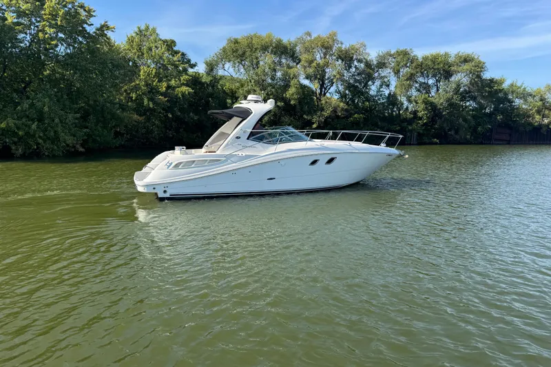 Slide: The Image of 2008 Sea Ray 350 Sundancer yacht cruising on a serene lake with lush greenery. - 55