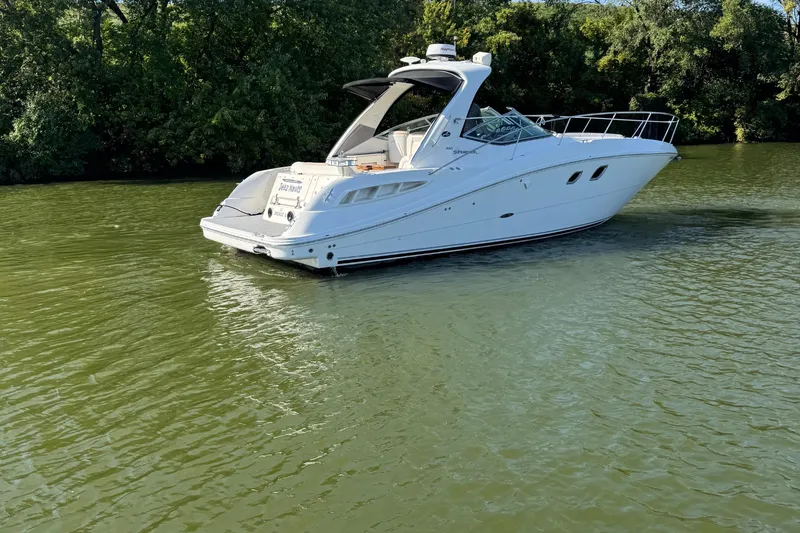 Slide: The Image of 2008 Sea Ray 350 Sundancer yacht on calm green water, surrounded by lush trees. - 56