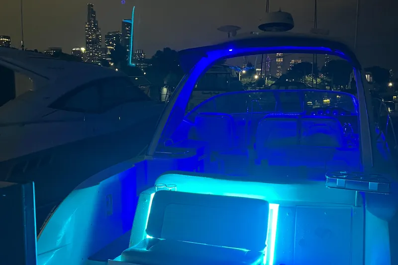 Slide: The Image of 2008 Sea Ray 350 Sundancer yacht illuminated with blue lights at night, city skyline in background. - 61