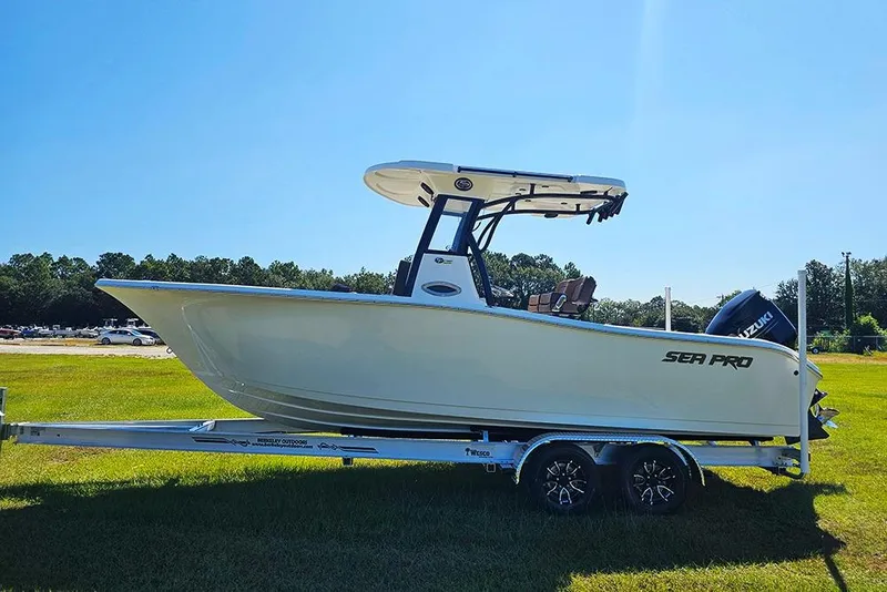 Slide: The Image of 2026 Sea Pro 242 Center Console Sport boat on trailer, parked on grass under clear blue sky. - 7