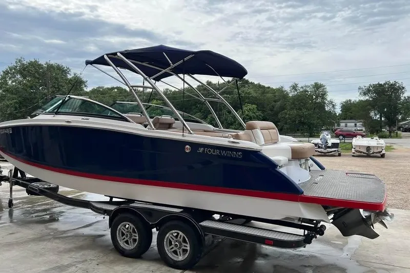 Slide: The Image of 2011 Four Winns SL262 boat on trailer, blue and white with red trim, parked outdoors. - 3