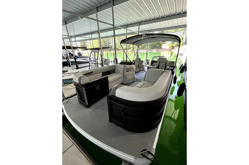 Slide: The Image of 2026 Godfrey Sweetwater 2486 SFLC pontoon boat with spacious seating under a covered dock. - 13