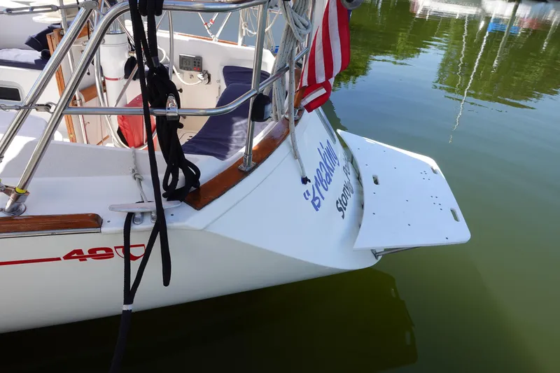 Slide: The Image of 1987 Tartan Marine 40 sailboat stern with American flag and docked in calm water. - 18