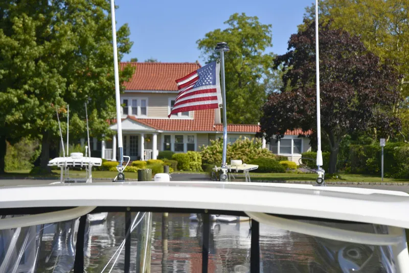 Slide: The Image of 2024 Pursuit DC 246 Dual Console boat with American flag, docked near a house. - 16