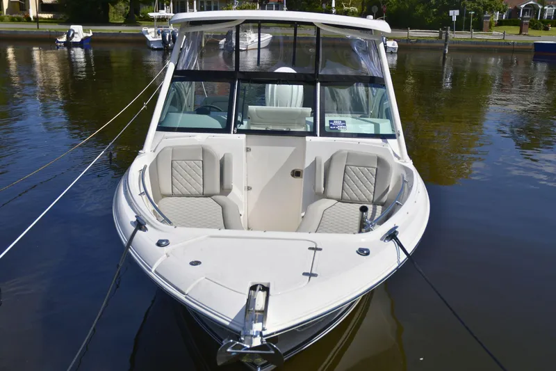 Slide: The Image of 2024 Pursuit DC 246 Dual Console boat docked on calm water. - 2