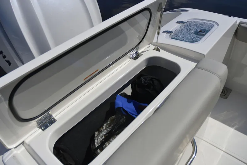 Slide: The Image of 2024 Pursuit DC 246 Dual Console storage compartment with open lid and gear inside. - 4