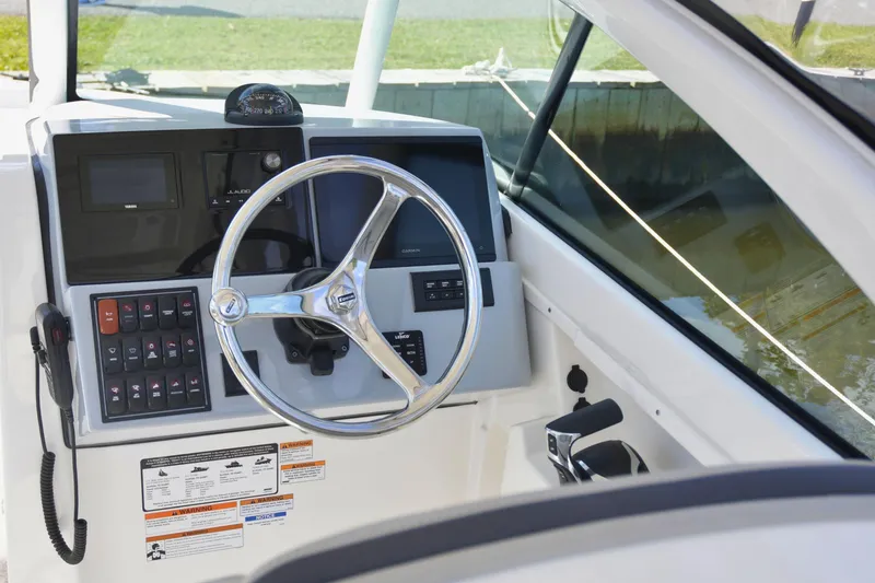 Slide: The Image of 2024 Pursuit DC 246 Dual Console boat dashboard with steering wheel and controls. - 8