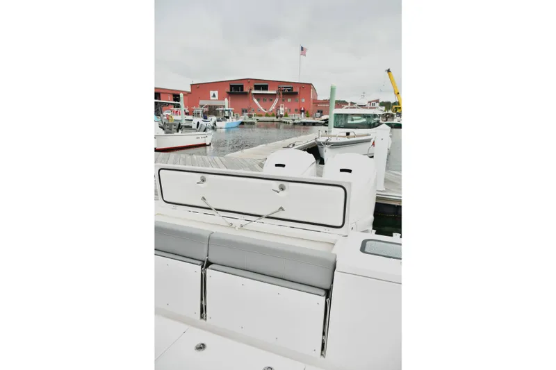 Slide: The Image of 2022 Everglades 335 Center Console boat docked at marina with red building backdrop. - 16