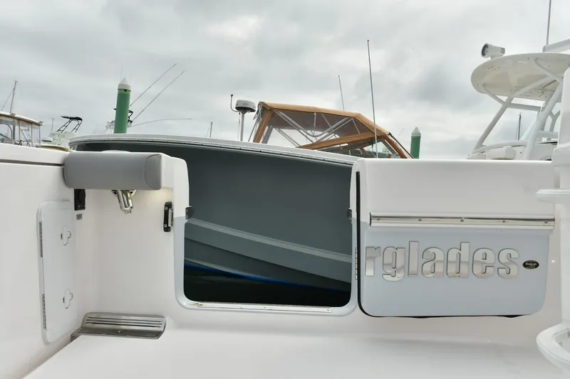 Slide: The Image of 2022 Everglades 335 Center Console boat with open side door, docked under cloudy sky. - 22
