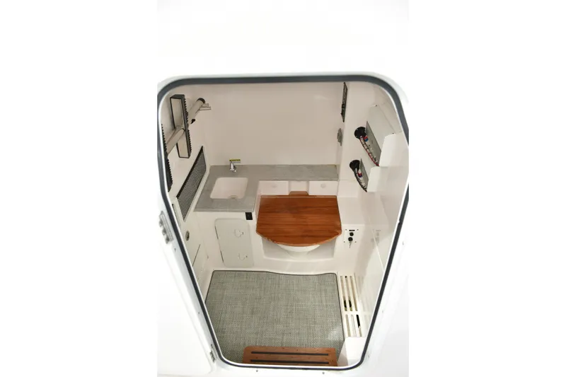 Slide: The Image of Interior view of 2022 Everglades 335 Center Console boat cabin with sink and wooden seat. - 27