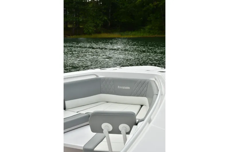 Slide: The Image of 2022 Everglades 335 Center Console boat interior with cushioned seating on a serene lake. - 30