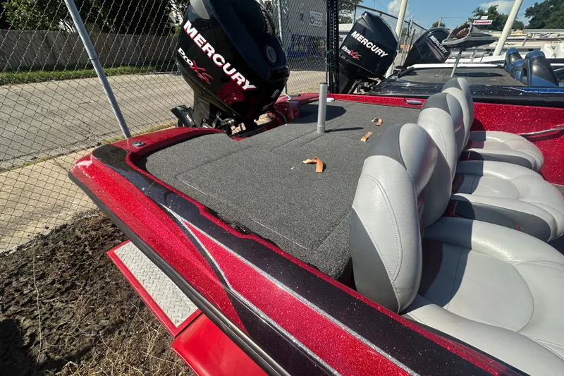 Slide: The Image of 2011 Nitro Z-6 boat with Mercury engine, red and gray seating, parked near a chain-link fence. - 22