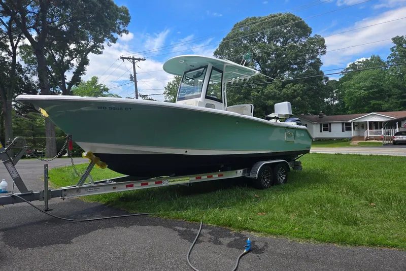 Slide: The Image of 2023 Sea Hunt Ultra 265 SE boat on trailer, parked on gravel lot. - 2