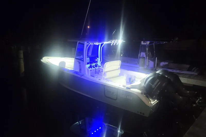 Slide: The Image of 2023 Sea Hunt Ultra 265 SE boat on trailer, parked on grass with trees in background. - 5