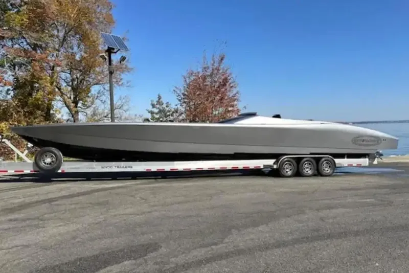 Slide: The Image of 2020 Outerlimits SL-50 powerboat on trailer, parked near a lake with autumn trees. - 10