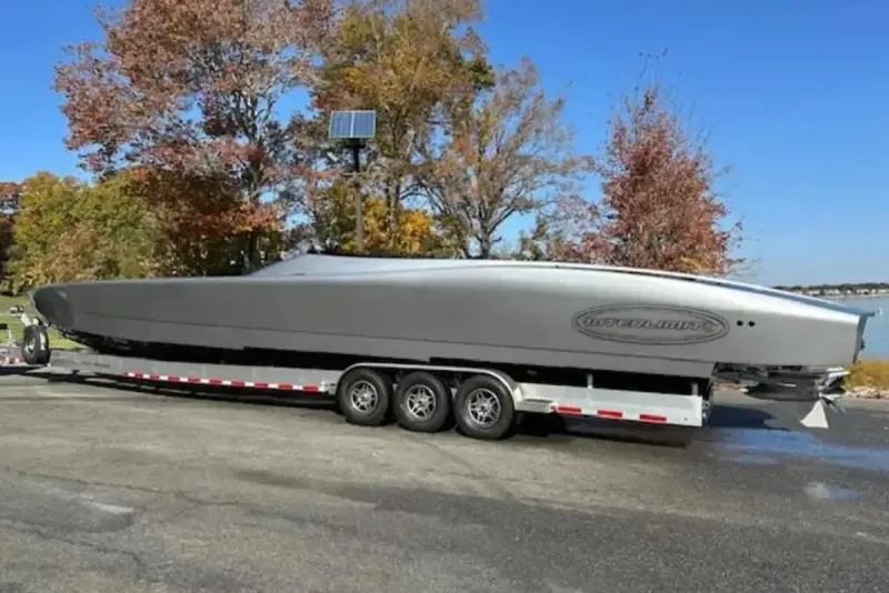 Slide: The Image of 2020 Outerlimits SL-50 powerboat on trailer, surrounded by autumn trees. - 13