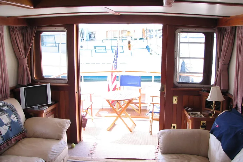 Slide: The Image of Interior of a 1989 Custom 52 Pilothouse yacht with cozy seating and outdoor deck view. - 5