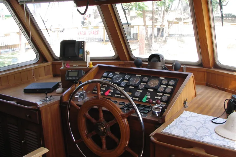Slide: The Image of Pilothouse interior of 1989 Custom 52, featuring wooden steering wheel and navigation instruments. - 6