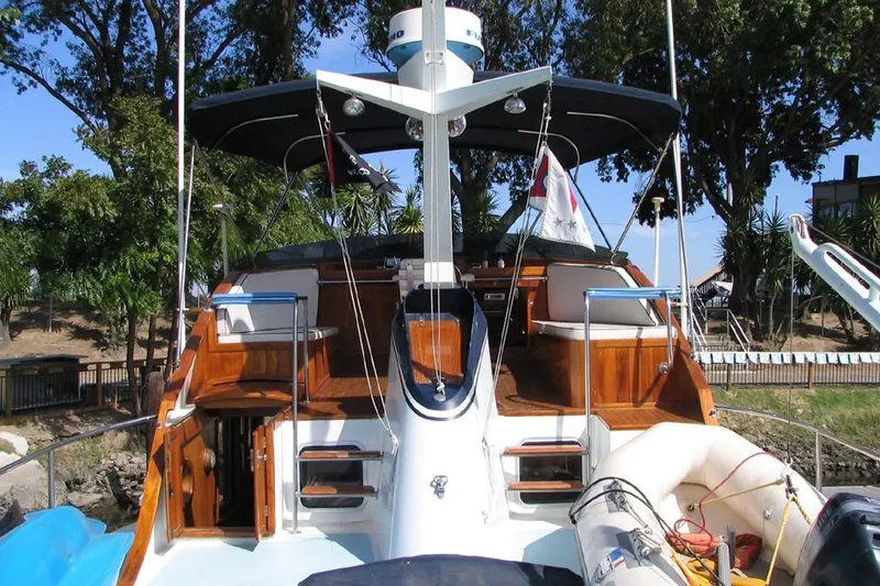 Slide: The Image of 1989 Custom 52 Pilothouse yacht with wooden deck and canopy, docked near lush greenery. - 7