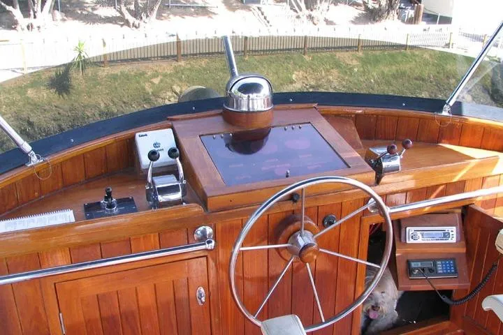 Slide: The Image of 1989 Custom 52 Pilothouse helm with wooden dashboard, steering wheel, and navigation equipment. - 9
