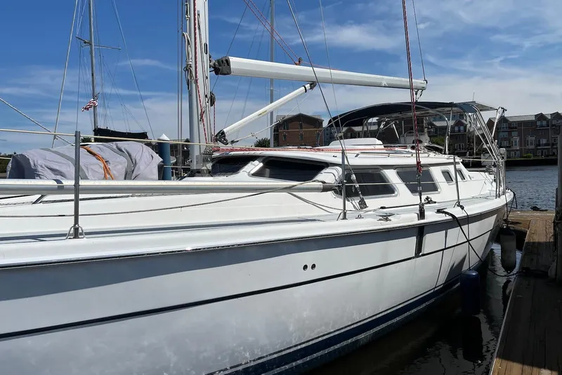 Slide: The Image of 2005 Hunter 44 Deck Salon sailboat docked at marina under clear blue sky. - 2