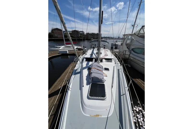 Slide: The Image of 2005 Hunter 44 Deck Salon sailboat docked at marina under clear blue sky. - 23