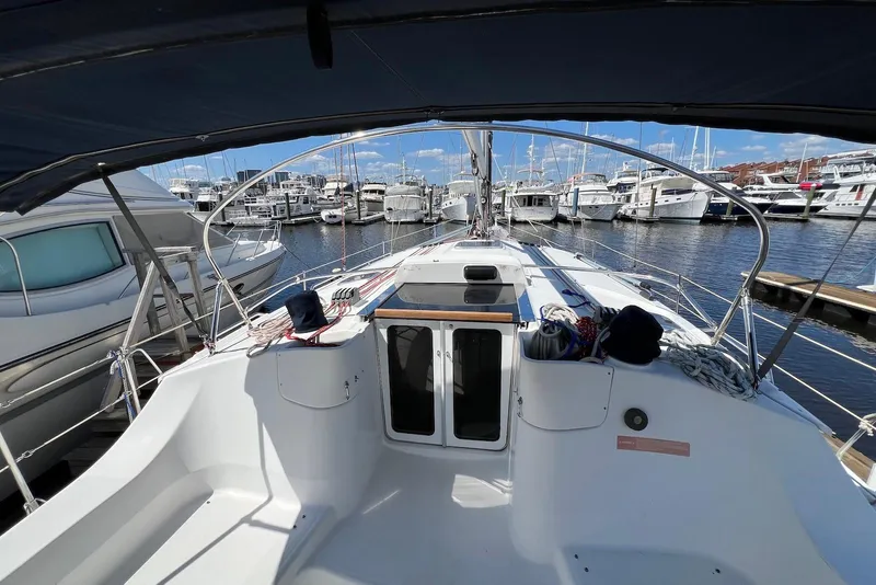Slide: The Image of 2005 Hunter 44 Deck Salon sailboat docked at marina, showcasing spacious cockpit and sleek design. - 25