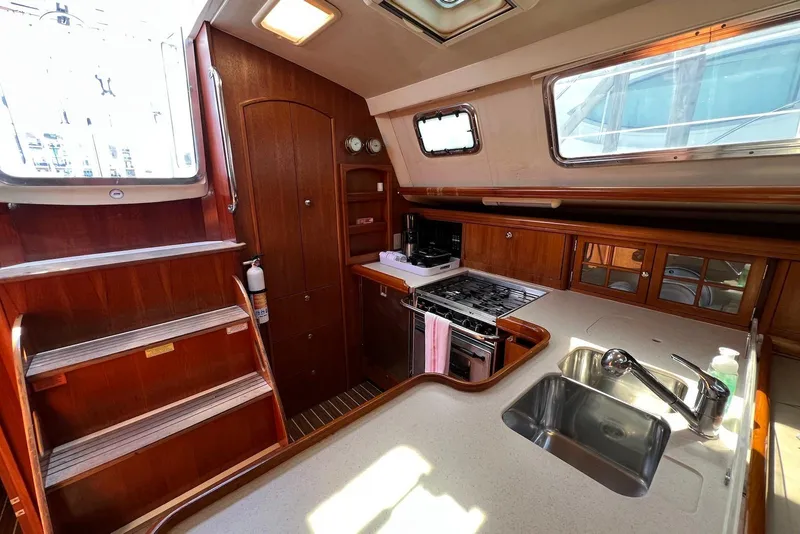 Slide: The Image of 2005 Hunter 44 Deck Salon interior with kitchen, stairs, and wooden cabinetry. - 32